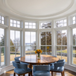 Round dining table and chairs in a nook with tall windows and stunning view